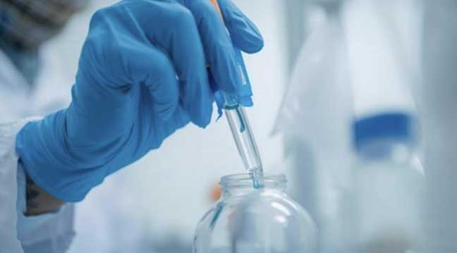 A scientist using a pipette to precisely transfer liquid in a laboratory setting, illustrating the technical side of beverage formulation.
