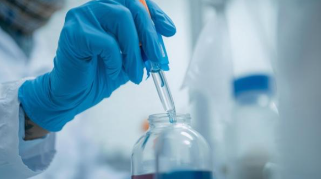 A scientist using a pipette to precisely transfer liquid in a laboratory setting, illustrating the technical side of beverage formulation.