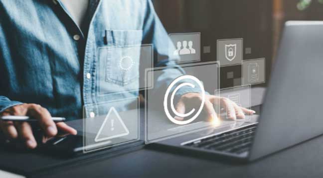 Business person working on laptop with copyright and intellectual property protection icons for beverage brand creative assets.