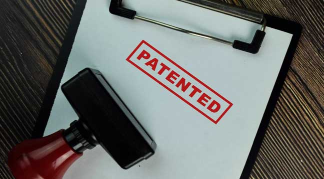 Patent stamp and red rubber stamper representing patent protection for beverage production innovations and distillery equipment. 